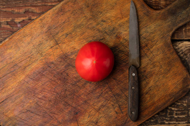 istock Red tomato and knife on wooden cutting board. View top 1172021054