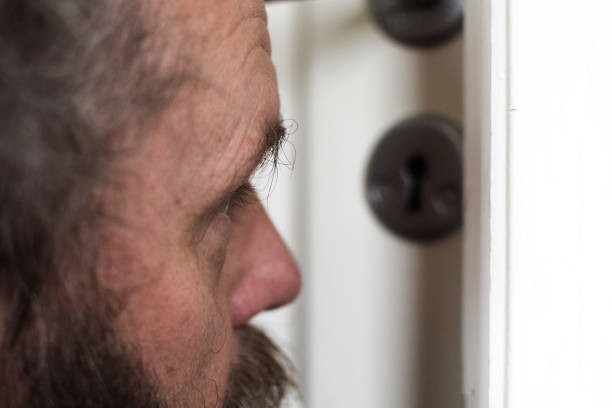 istock European 50 years old looks into the keyhole. 1172024959