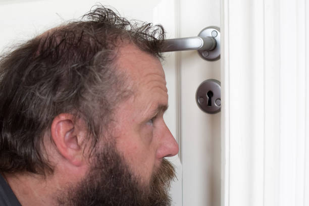 istock European 50 years old looks into the keyhole. 1172025006