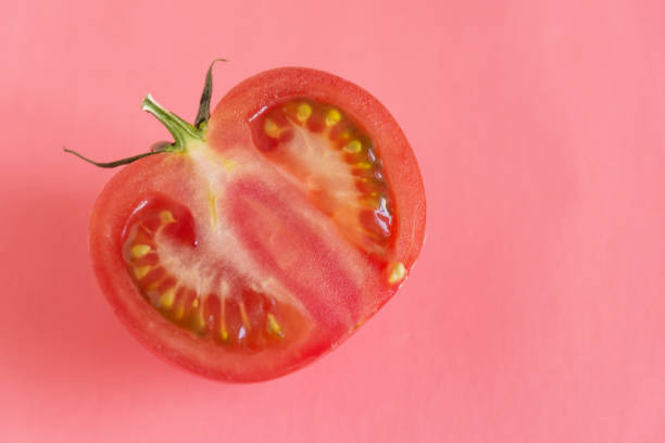 istock Half sliced tomato closeup on pink background. 1172025017