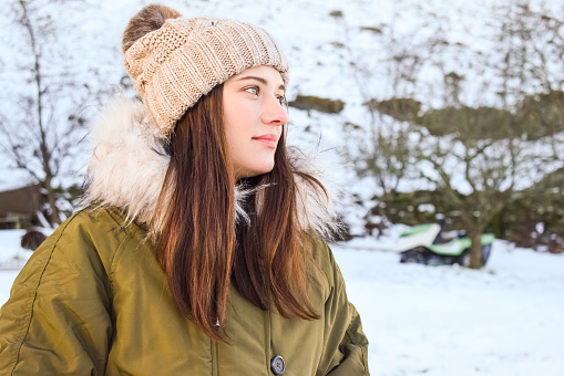Portrait of a girl in a hat with a pompon against the background of a winter landscape.