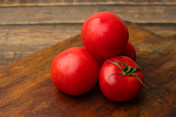 Red tomatoes on an old wooden cutting board. Fresh harvest. Copy space