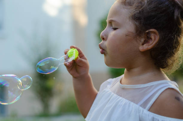 istock Cute girl is blowing soap bubbles 1172032854