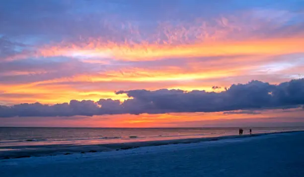 Beautiful cloudy sunset at Siesta Key, Florida, with people in silhouette in the foreground.