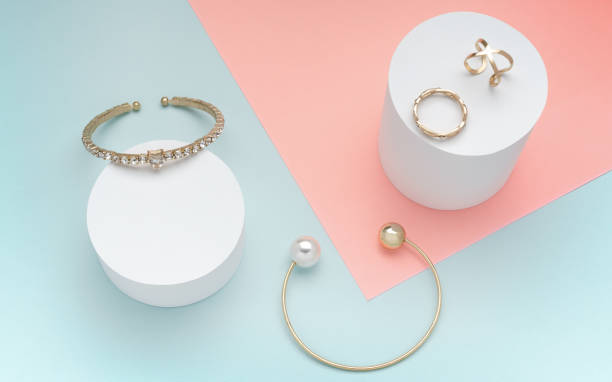 pulseras de oro de perlas y diamantes y anillos dorados sobre fondo de color pastel - cilindro fotos fotografías e imágenes de stock