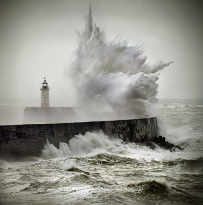 Mighty waves in the English channel overwhelm Newhaven harbour lighthouse, East Sussex. UK\nColour image but look monochrome