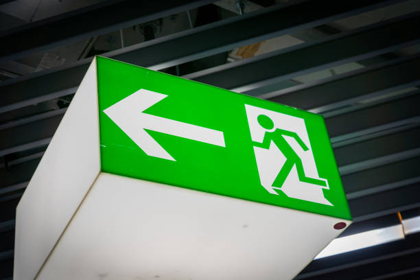 istock Emergency fire exit sign glowing green in the blacked out background 1172051920