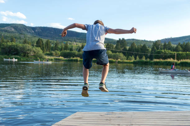 istock Boy Jumping Leaping on a Floating Dock on a Mountain Lake 1172059101