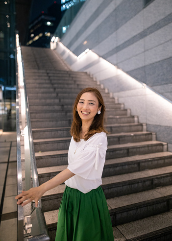 Japanese woman standing on stairs in city at night