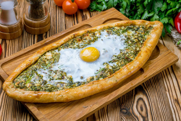 Turkish pide with spinach and egg on wooden table