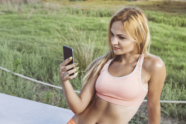 attractive female athlete looking at the phone before training, athletic sporty woman consulting the sport app on a break, technology fitness and healthy lifestyle concept, copy space for text