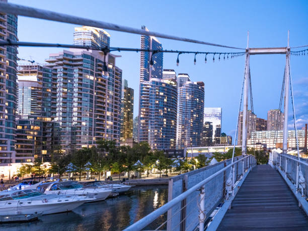 The Toronto city skyline at the Harbourfront area.  A pedestrian footbridge takes the public from one pier to another.