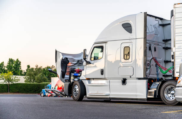 White big rig semi truck with open hood for engine inspection standing on the truck stop stock photo