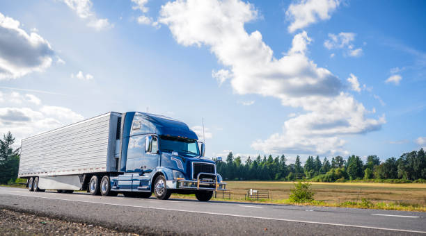 azul gran plataforma semi camión con grille guard trabsporting carga congelada en refrigerador semi trailer con alerón falda corriendo en la carretera recta - semi truck cargo container shipping truck fotografías e imágenes de stock