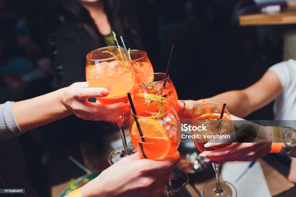 women raising a glasses of Spritz at the dinner table. women raising a glasses of Spritz at the dinner table Cocktail Stock Photo