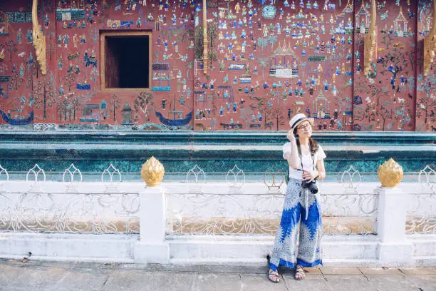 Photo of Asian tourist visiting Wat Xieng Thong an iconic temple in Luang Prabang, the UNESCO world heritage town in north central of Laos.