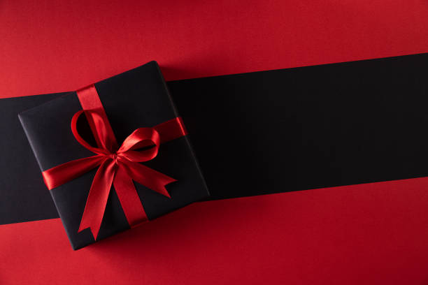 top view of black christmas boxes with red ribbon on black background with copy space for text. black friday and boxing day composition. - gift gold box white imagens e fotografias de stock