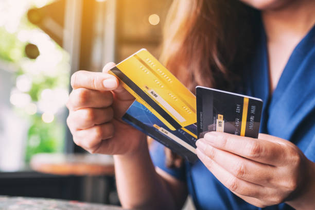 una mujer sosteniendo y eligiendo tarjeta de crédito para usar - debt fotografías e imágenes de stock