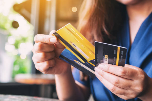 une femme tenant et choisissant la carte de crédit pour employer - carte de crédit photos et images de collection