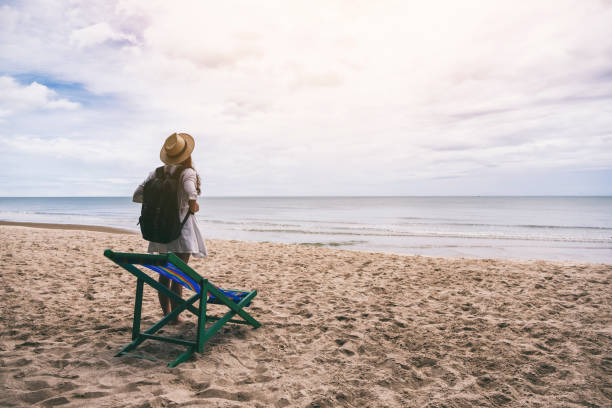 istock A female traveler with hat and backpack standing alone on the beach 1172101506