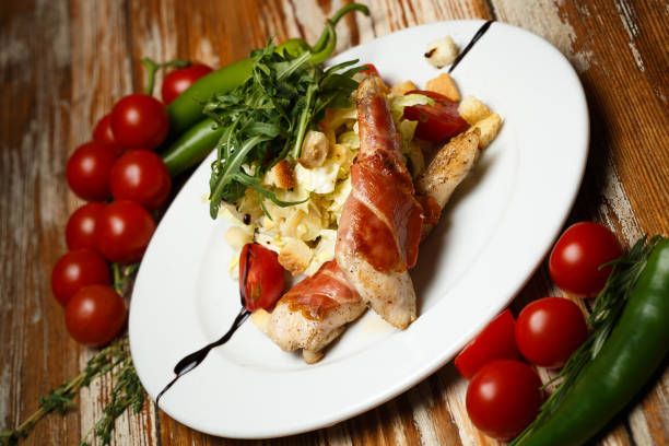 istock Caesar salad with chicken and bacon on wooden table 1172105477