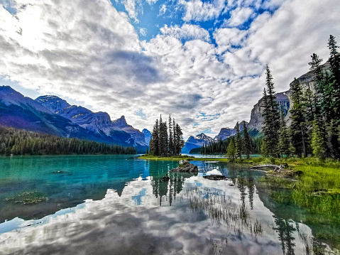 The spectacular Spirit Island on Maligne Lake, Jasper National Park, Alberta, Canada. Reflections of the sky bounce off the clear waters surrounding this Canadian Rockies icon, with the Hall of the Gods in the background.