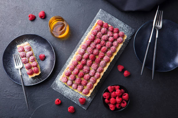 tarte aux framboises à la crème à la vanille et chocolat blanc sur planche d'ardoise. fond noir. vue du haut. - tart dessert chocolate fruit photos et images de collection