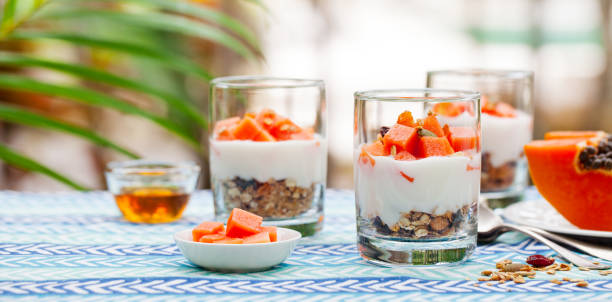 Dessert with papaya, yogurt and granola in glasses. Outdoor background. stock photo