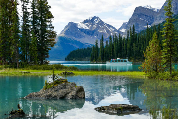 barca da crociera che naviga oltre spirit island, jasper national park - lago maligne foto e immagini stock