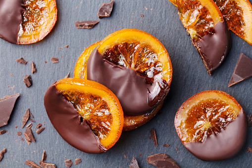 Candied orange slices in chocolate. Slate background. Close up. Top view