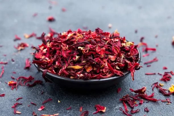 Hibiscus tea in black bowl. Slate background. Close up.