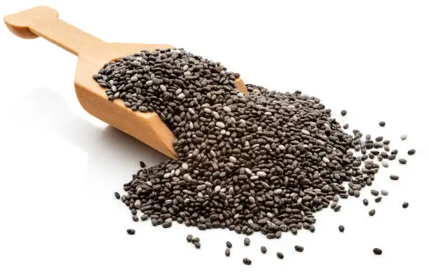 Chia seeds in a wooden serving scoop. 
Isolated on a white background.
