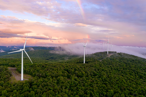 Aerial view of wind turbines taken with a drone in Vermont. Pink clouds and rainbow in background.