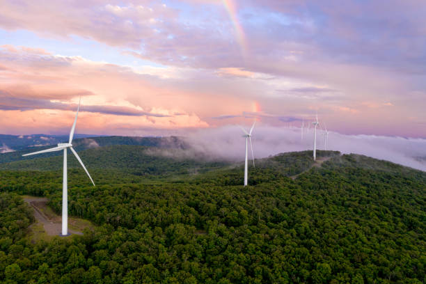 Wind Turbines on Mountain Ridge at Sunset with Rainbow Aerial view of wind turbines taken with a drone in Vermont. Pink clouds and rainbow in background. green mountains appalachians photos stock pictures, royalty-free photos & images