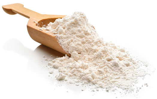 Flour in a serving scoop. 
Isolated on a white background.