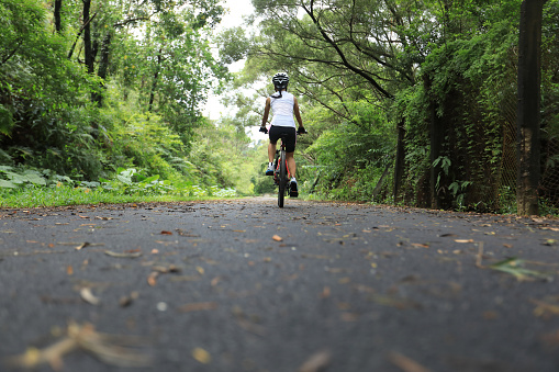 Woman cyclist riding mountain bike on tropical rainforest trail