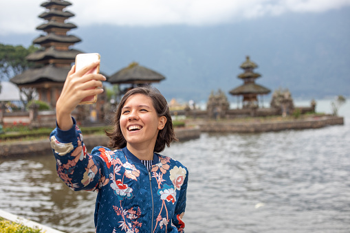Young woman taking selfie at Bali Temple, Pura Ulun Danu Bratan