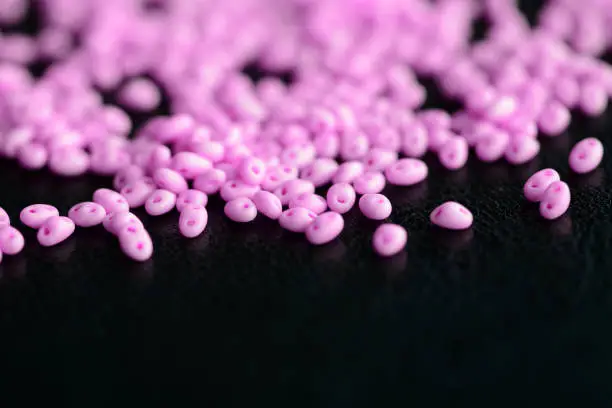 Bright pink twin beads scattered on a dark surface close up