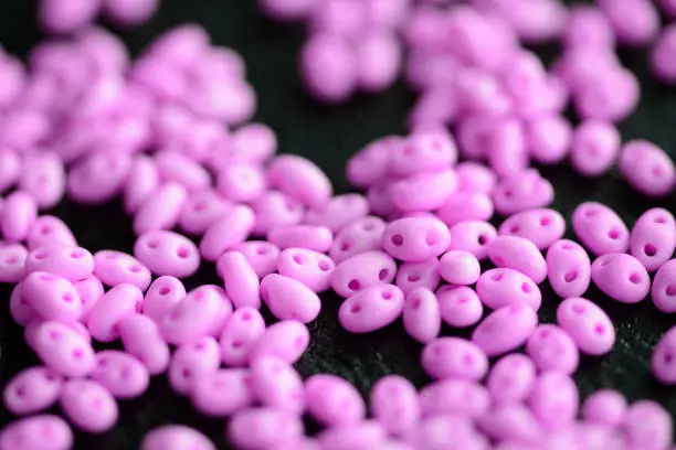 Bright pink twin beads scattered on a dark surface close up