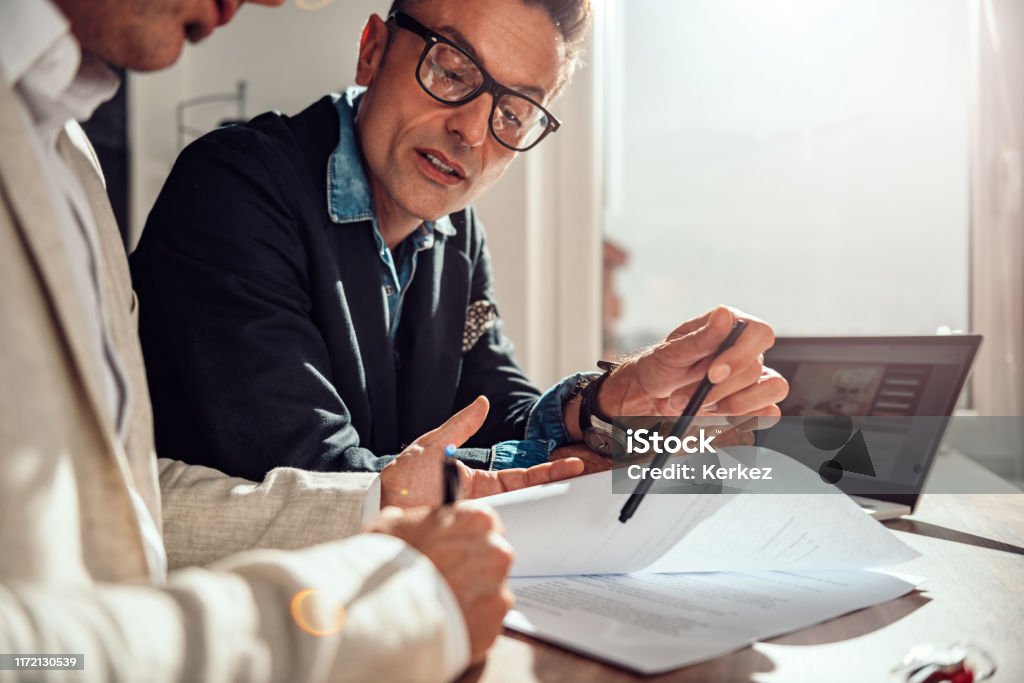 Businessman pointing where client have to sign the contract Businessman pointing place in contract where client have to sing Insurance Agent Stock Photo