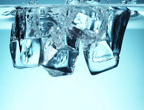 Group of ice cubes falling in water. Refreshment and drink concept