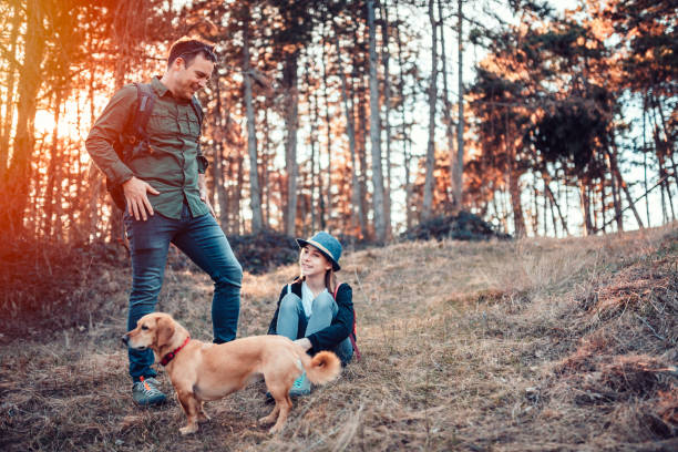 istock Father and daughter resting with dog in forest during sunset 1172135574