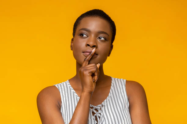 istock Concentrated black woman touching her lips and looking aside 1172136649