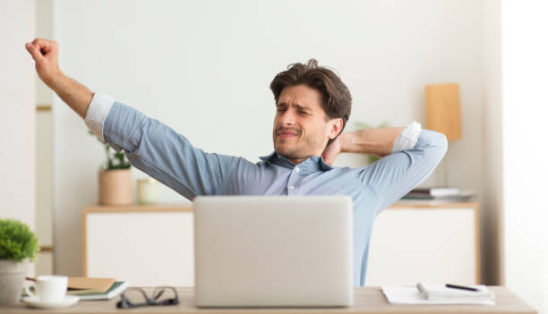 istock Young Man Stretching Hands Woking On Laptop At Home 1172137046