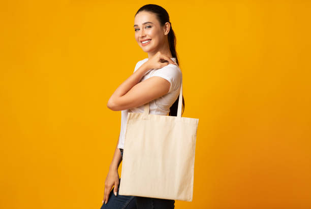 istock Young Woman Holding White Eco Bag On Yellow Studio Background 1172137056