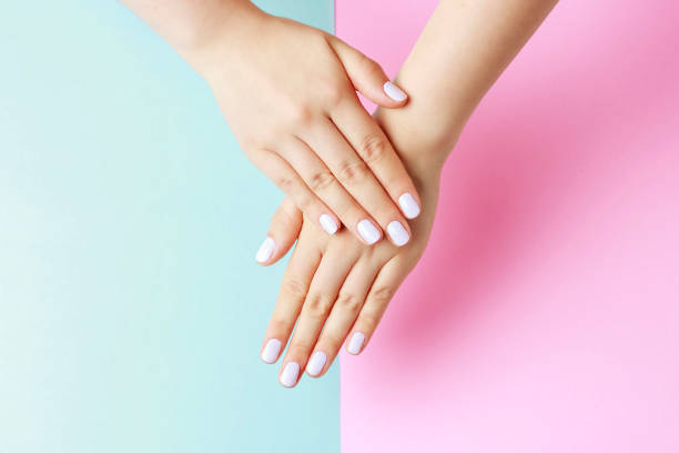 istock Female hands with white manicure on a pink and blue background, top view 1172137105