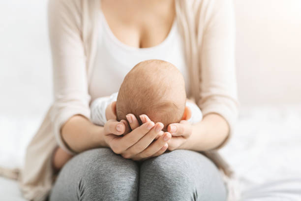 mutter hält kopf ihres neugeborenen babys in den händen - lullaby stock-fotos und bilder