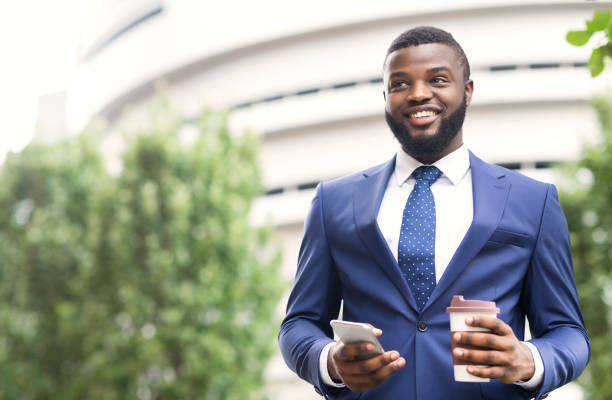 istock Handsome businessman standing outdoors with coffee and smartphone in arms 1172138213