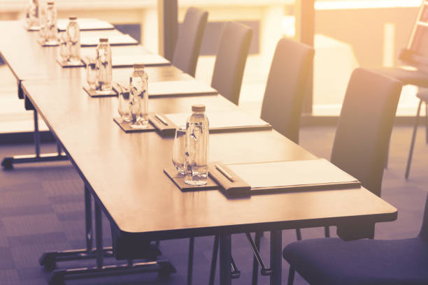istock Plastic water bottles, Drinking glasses with pencil and white papers setup on the table prepared for seminar or business meeting in the hotel conference room 1172138376