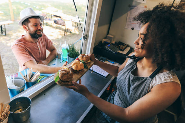 Smiling african woman selling burgers in food truck African woman selling burgers in food truck, high angle view. concession stand stock pictures, royalty-free photos & images